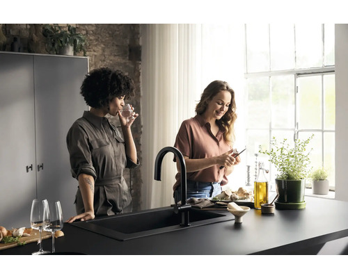 Helle Küche mit schwarzer Spüle, Armatur und zwei Frauen, die kochen