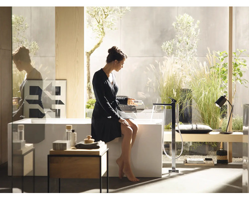 Helles Badezimmer mit freistehender Badewanne, Armatur und Frau im Bademantel