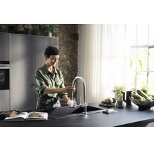 Femme remplissant un verre d''eau dans un évier de cuisine moderne