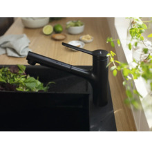 Schwarze Küchenarmatur neben einer Spüle mit Salat