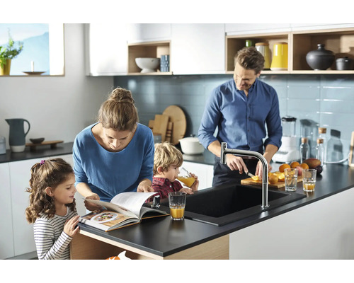 Une famille prépare des aliments dans une cuisine lumineuse avec un robinet de cuisine et un évier.