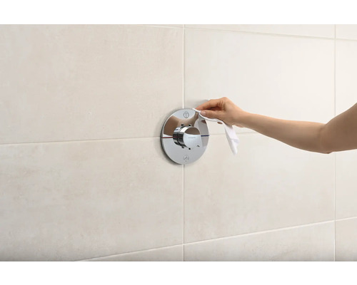 Frau reinigt Duscharmatur im Badezimmer