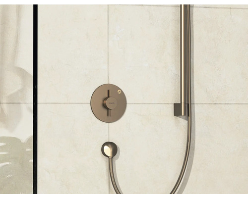 Robinet de douche apparent avec douchette à main devant des carreaux muraux