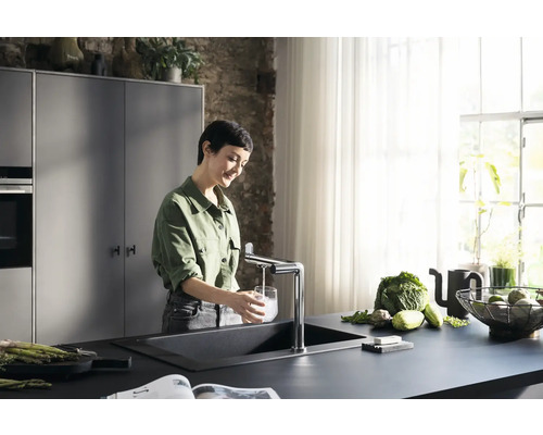 Femme remplissant un verre d''eau à l''évier avec robinet dans une cuisine moderne