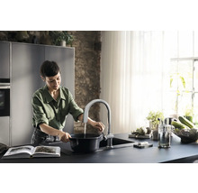 Une femme remplit d''eau une casserole dans une cuisine moderne