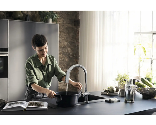 Frau füllt Wasser in einem modernen Küchendesign in einen Topf