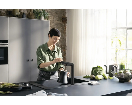 Cuisine moderne avec évier, robinet et femme remplissant d''eau une cruche
