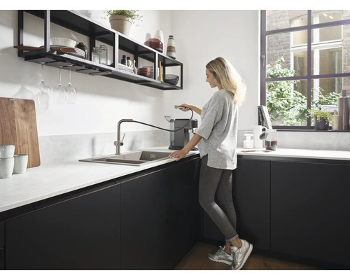 Cuisine moderne avec évier, robinet et étagères murales. Une femme se tient à l''évier.