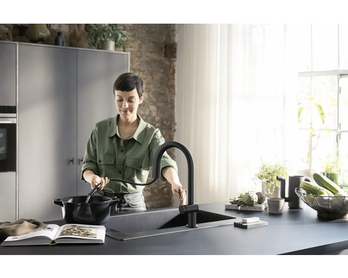 Frau am Waschbecken mit ausziehbarer Küchenarmatur beim Kochen in der Küche
