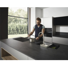 Moderne Küche mit Kochinsel, Spüle, Kochfeld und einer Person beim Kochen