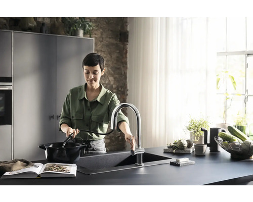 Frau am Spültisch mit Küchenarmatur beim Kochen
