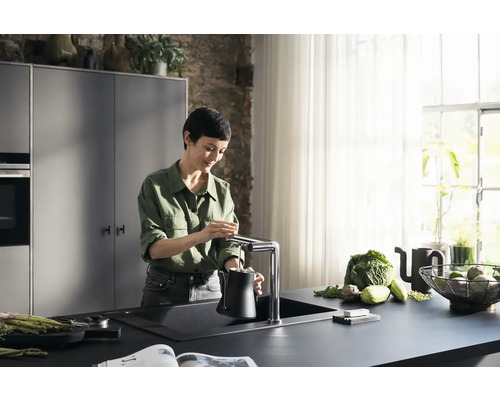 Femme remplissant une cruche d''eau à un robinet de cuisine dans une cuisine moderne.