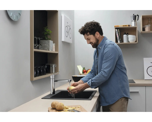 Homme lavant des pommes de terre dans une cuisine moderne avec évier et robinet