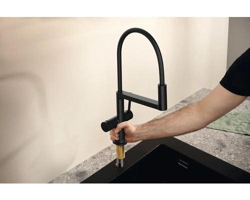 Mitigeur de cuisine noir avec bec flexible en cours d''installation.