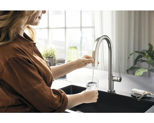 Frau füllt ein Glas Wasser am Wasserhahn in der Küche