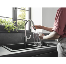 Frau füllt Wasser in einem Küchenwaschbecken in einen Krug