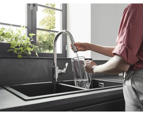 Frau füllt Wasser in einem Küchenwaschbecken in einen Krug