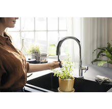 Femme arrose une plante avec un robinet de cuisine dans un évier