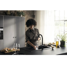 Une femme remplit un verre d''eau sur un évier de cuisine avec un robinet dans une cuisine moderne