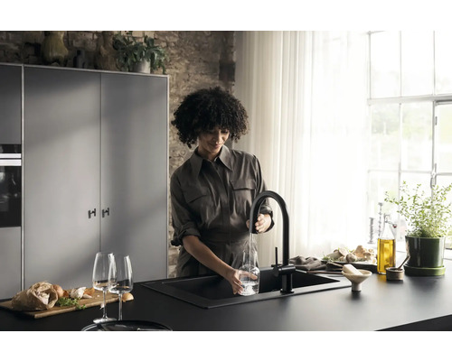 Frau füllt Wasser in ein Glas an einer Spüle mit Armatur in einer modernen Küche.
