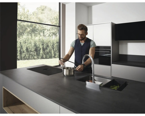 Moderne Küche mit Kochinsel, Spüle und einer Person beim Kochen