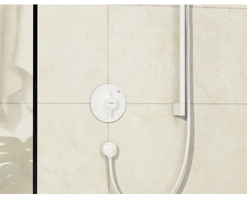 Thermostat de douche apparent avec flexible de douche et pomme de douche montés au mur.