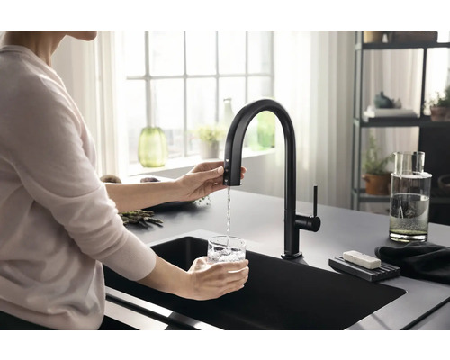 Frau füllt Wasser in ein Glas an einer schwarzen Küchenarmatur mit hohem Auslauf