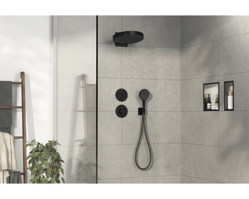 Cabine de douche claire avec robinetterie noire, douche de pluie et douchette à main, ainsi que des niches de rangement dans le mur