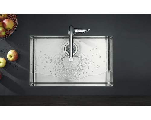 Évier en acier inoxydable avec robinet et eau courante, ainsi que des pommes dans un panier