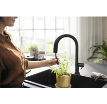 Femme arrosant une plante avec un robinet de cuisine noir à douchette extractible