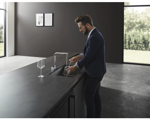 Homme rinçant un verre dans une cuisine moderne avec un mitigeur d''évier.