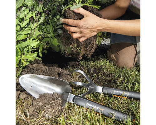 Scène de jardinage avec une pelle à planter, une cultivatrice et une personne plantant une plante