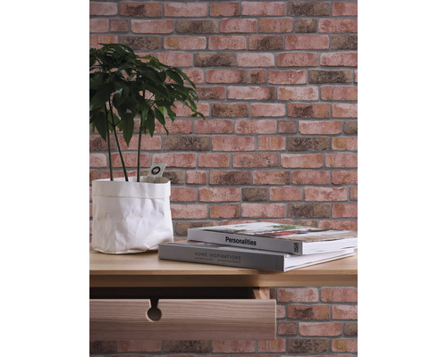 Wandgestaltung mit Steinoptik-Tapete, Pflanze und Büchern auf einem Tisch