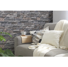 Wohnzimmer mit grauer Couch, Kissen, Decke und Steinwandtapete
