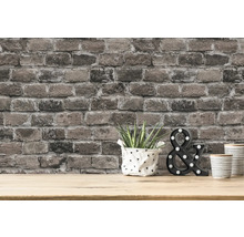 Mur avec papier peint en briques, plante, objet décoratif et gobelets sur une table
