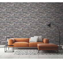 Wohnzimmer mit grauer Steinoptik Tapete, Couch und Lampe.