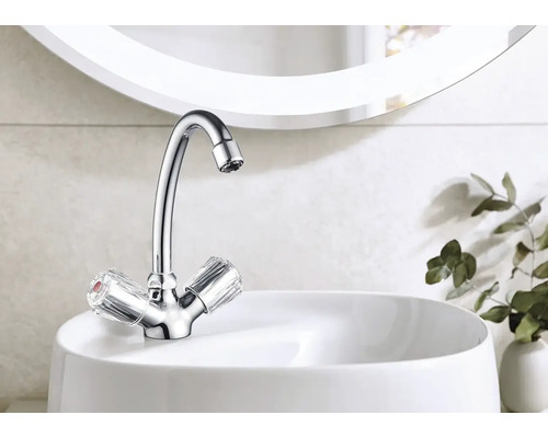 Robinet brillant avec poignées transparentes sur un lavabo blanc