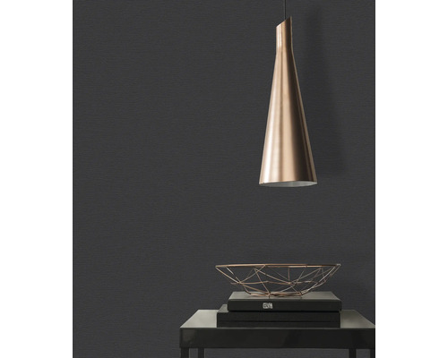 Nahaufnahme einer dunklen Wand mit Texturtapete, einer Pendelleuchte und einem dekorativen Metallkorb auf einem Tisch