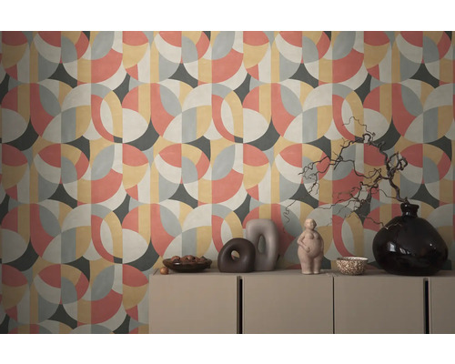 Wand mit geometrischer Tapete und dekorativen Objekten auf einem Schrank