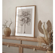 Image décorative avec un motif de palmier dans un cadre en bois, placée sur un buffet.