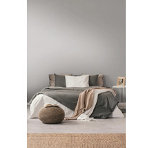 Helles Schlafzimmer mit Bett, Kissen, Decken, Beistelltisch und Teppich