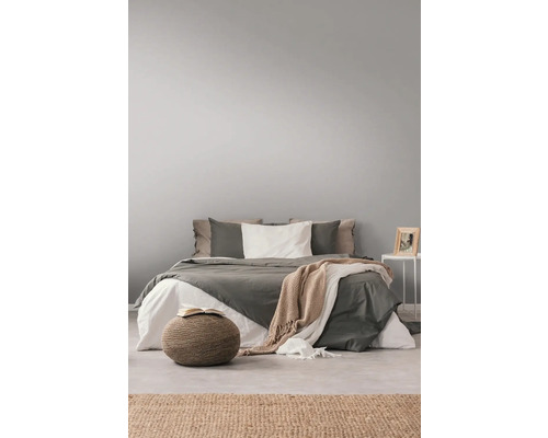 Helles Schlafzimmer mit Bett, Kissen, Decken, Beistelltisch und Teppich