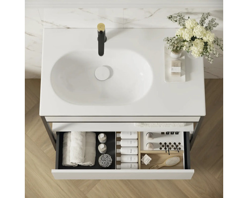 Vue de dessus d''un meuble sous-lavabo avec lavabo, robinetterie et tiroir ouvert contenant divers accessoires de salle de bain.