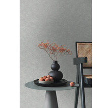Dekorative Szene mit Tisch, Vase, Trockenblumen und Stuhl vor einer strukturierten Wand