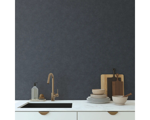 Küchenspüle mit Armatur, Geschirr, Schneidebrettern und Spülmittel auf einer Küchenarbeitsplatte vor einer Wand