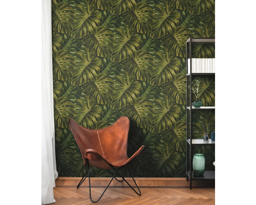 Pièce avec papier peint à feuilles de Monstera, fauteuil en cuir et bibliothèque