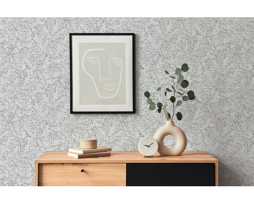 Raumansicht mit gemusterter Tapete, Kommode, Bild und Dekoration