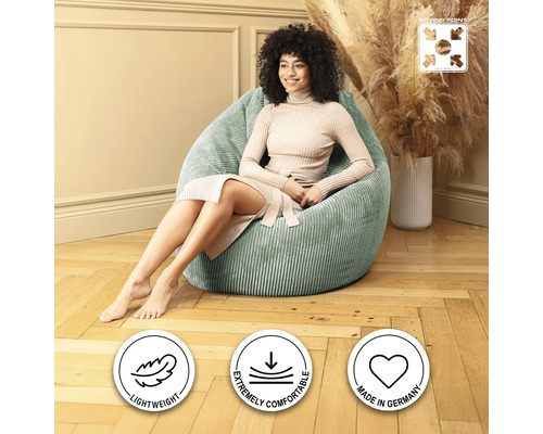 Femme assise dans une pièce lumineuse sur un pouf vert