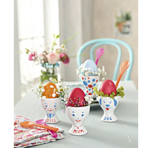 Table décorative avec œufs de Pâques peints dans des coquetiers, décorée de petites fleurs et de cuillères