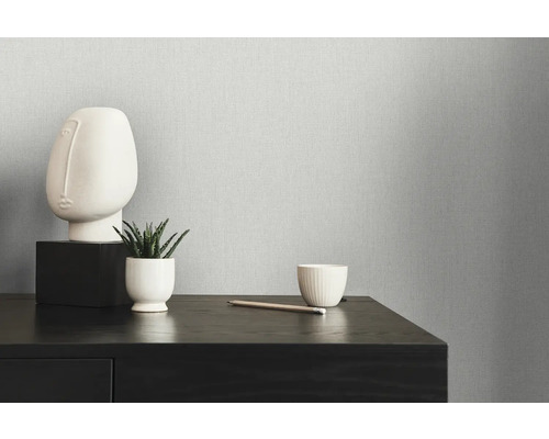 Nahaufnahme einer strukturierten Tapete mit minimalistischer Dekoration auf einer dunklen Holzkommode.